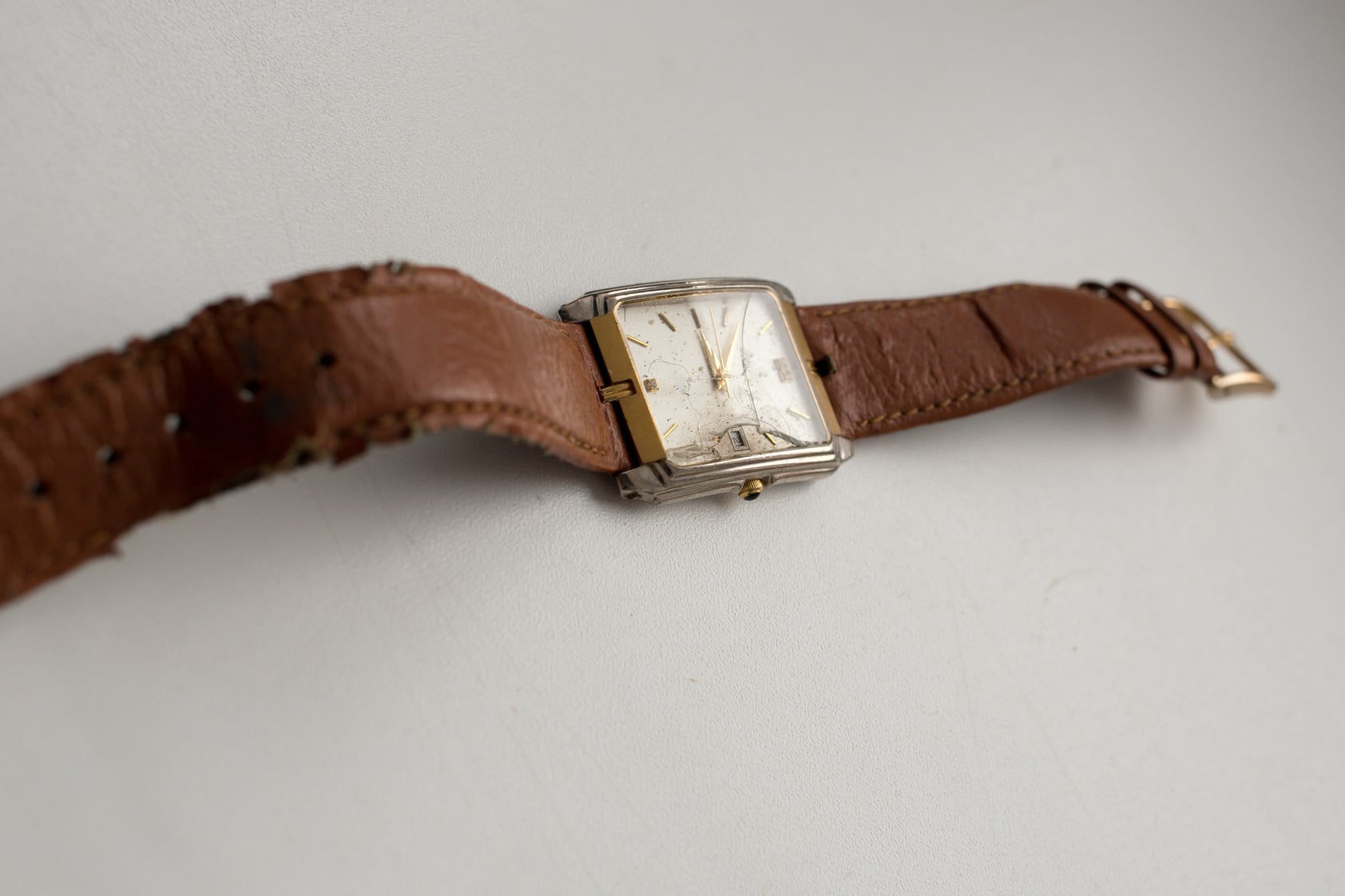 Old broken wrist watch. Damaged glass clock